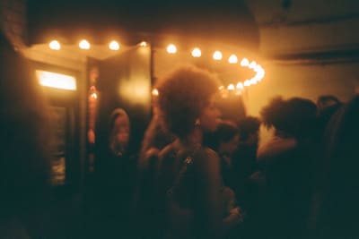 Crowd at night under an awning edged with glowing round bulbs