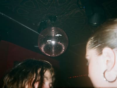 Disco ball hanging from a patterned club ceiling above two blurred heads